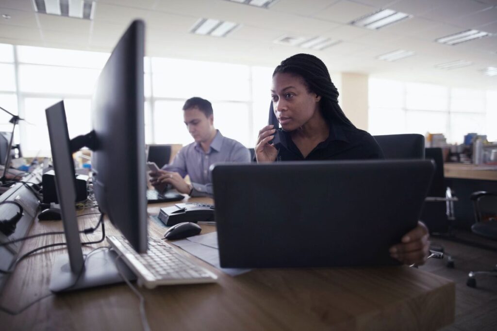 Setor de telemarketing com uma mulher e um homem fazendo atendimentos por telefone